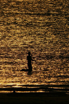 Peddelsurfer op zee tijdens zonsondergang