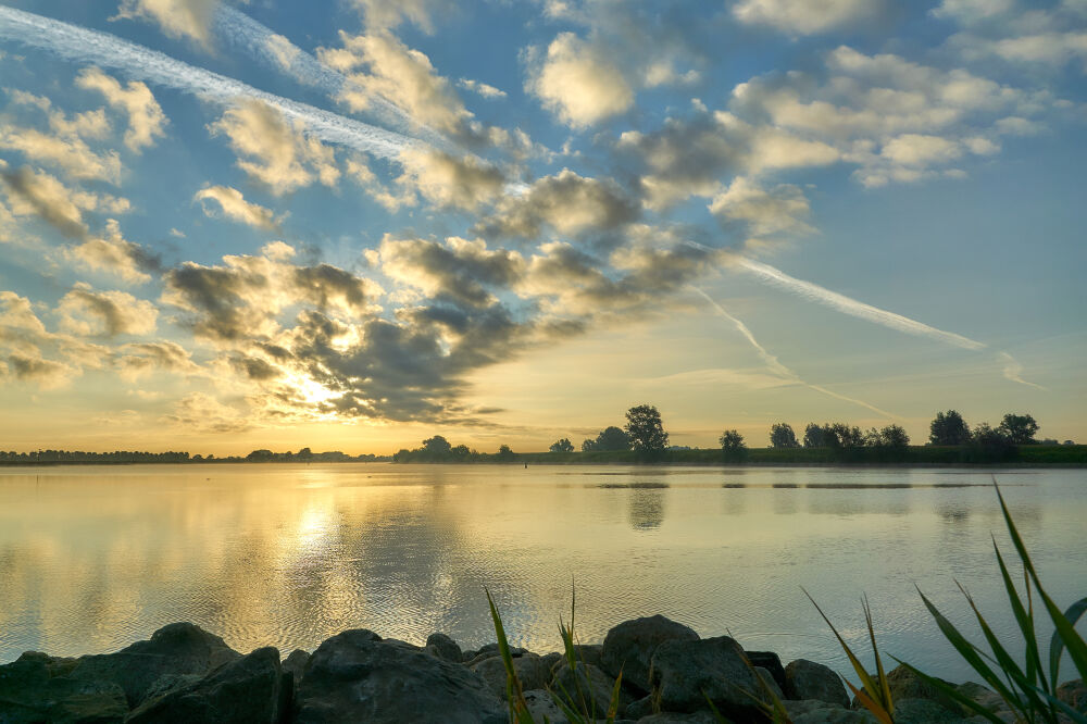 Wolken voor de net opgekomen zon aan de rivier de Lek