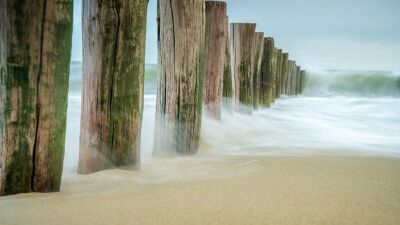 Beukende golven tegen strandpalen op kust Zeeland