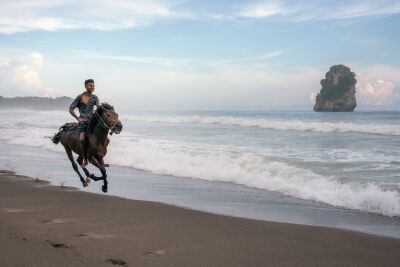 Sumbanese jongen op zijn paard aan het strand
